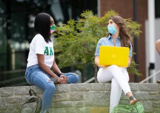 two students sitting together outside college of law with computer