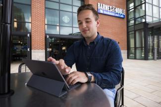 Student on iPad outside of bookstore
