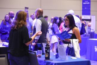 student speaking with UK representative at open house