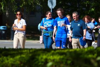 Group of visitors following tour guide on campus.